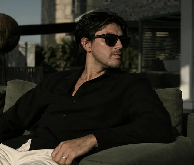 Fernando Valdez in sunglasses on a terrace sofa, looking away